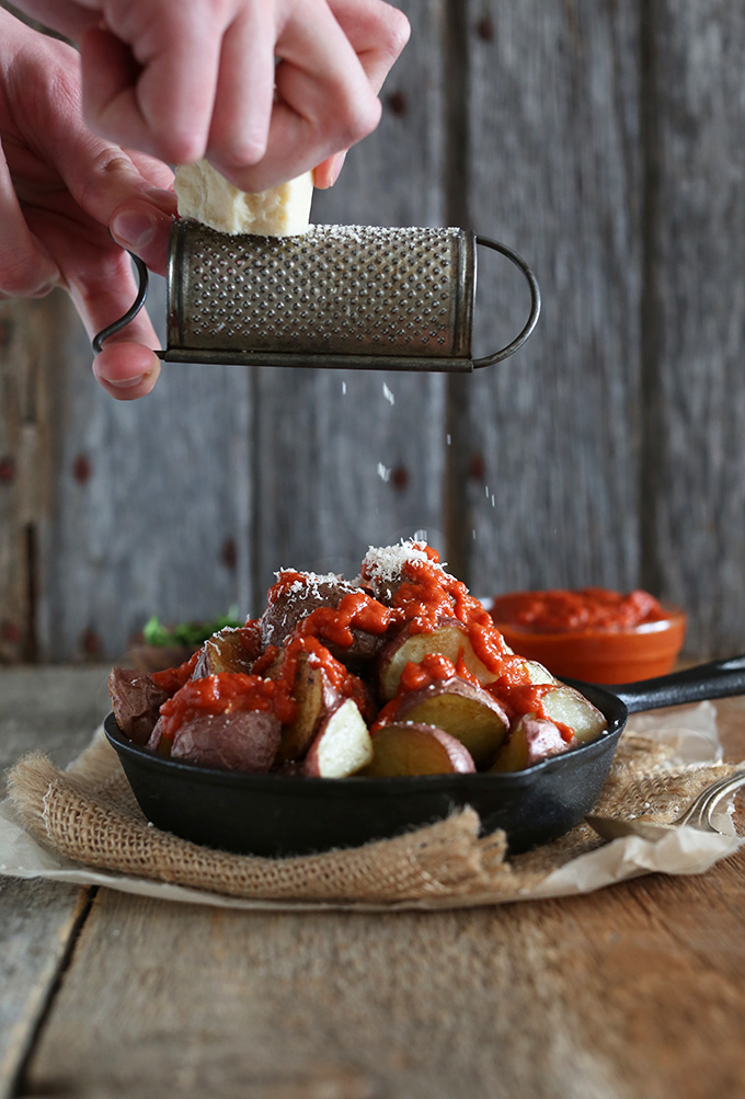 Grating parmesan cheese over Patatas Bravas for a delicious breakfast