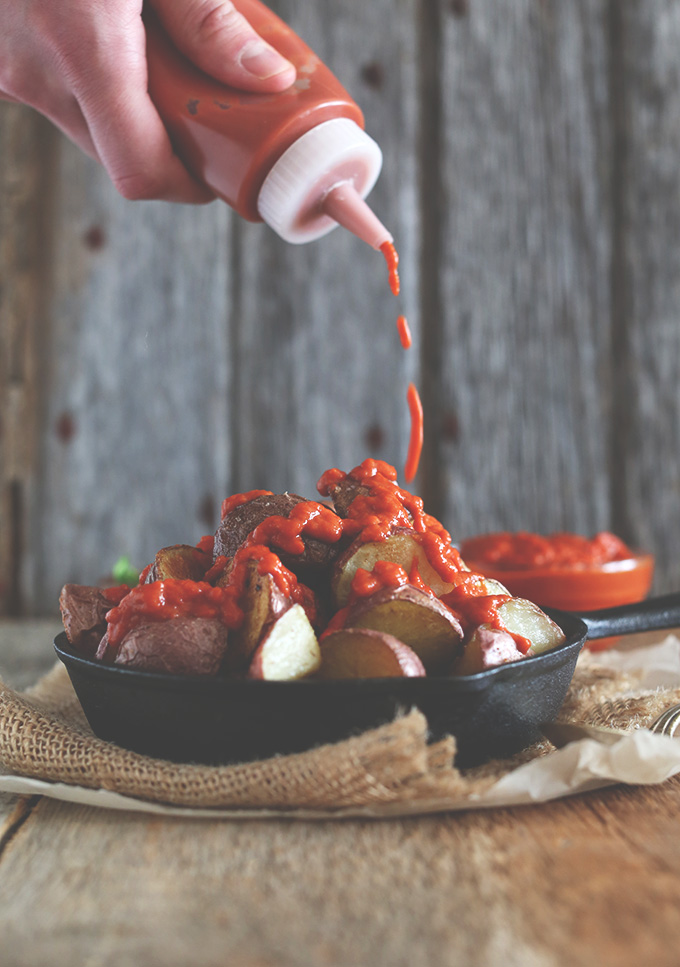 Drizzling sauce onto Patatas Bravas in a cast-iron skillet