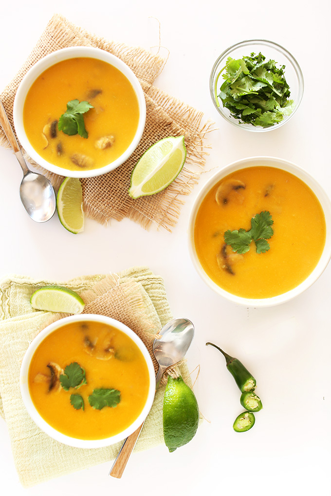 Bowls of Tom Kha Gai Soup with fresh cilantro and lime wedges