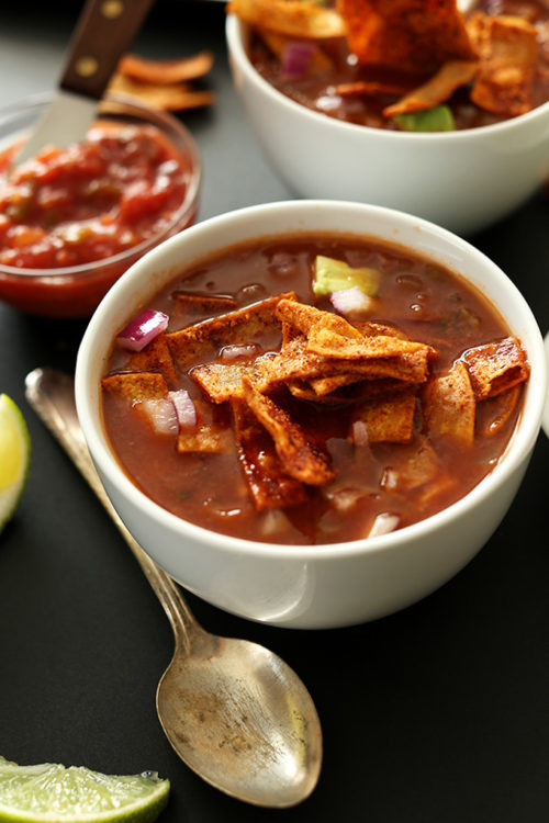 Bowls of Vegan Nacho Soup with limes and salsa