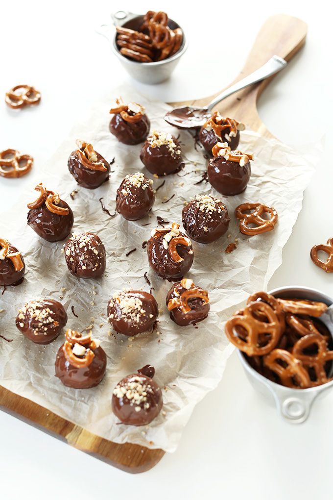 Cutting board of Vegan Pretzel Peanut Butter Truffles and measuring cups of pretzels