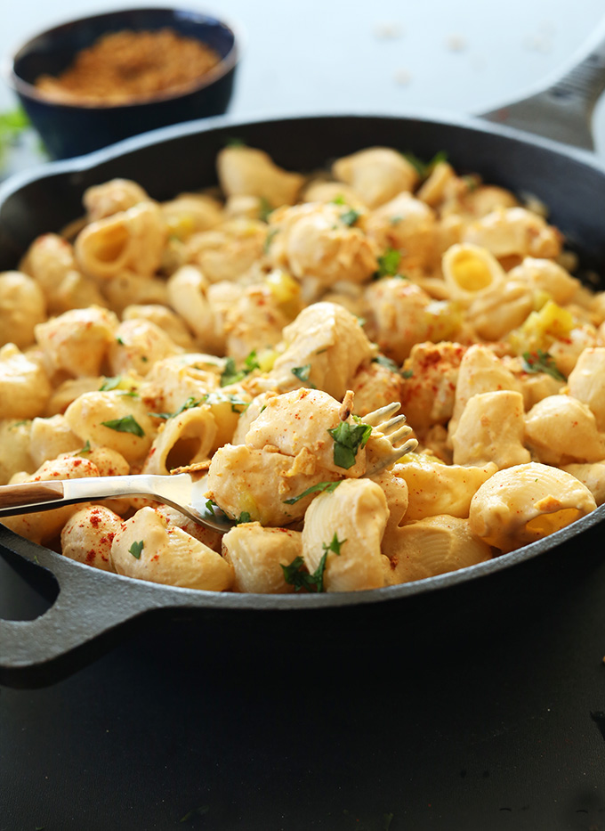 Fork full of Vegan Mac n Cheese resting on a cast iron skillet