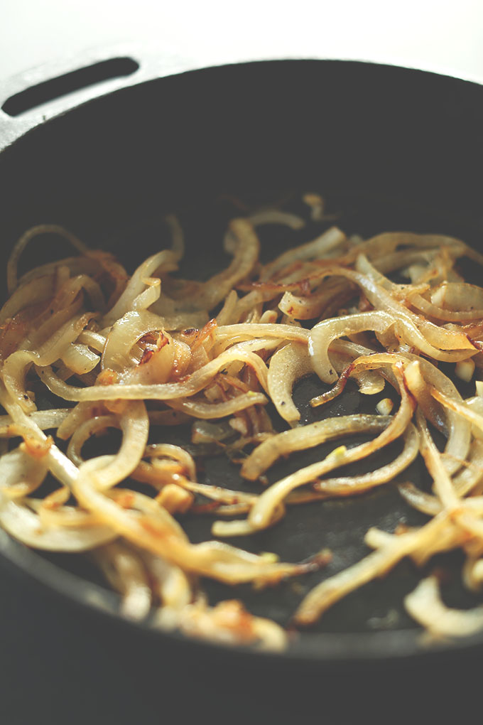 Cast iron skillet filled with caramelized onions for zucchini gratin