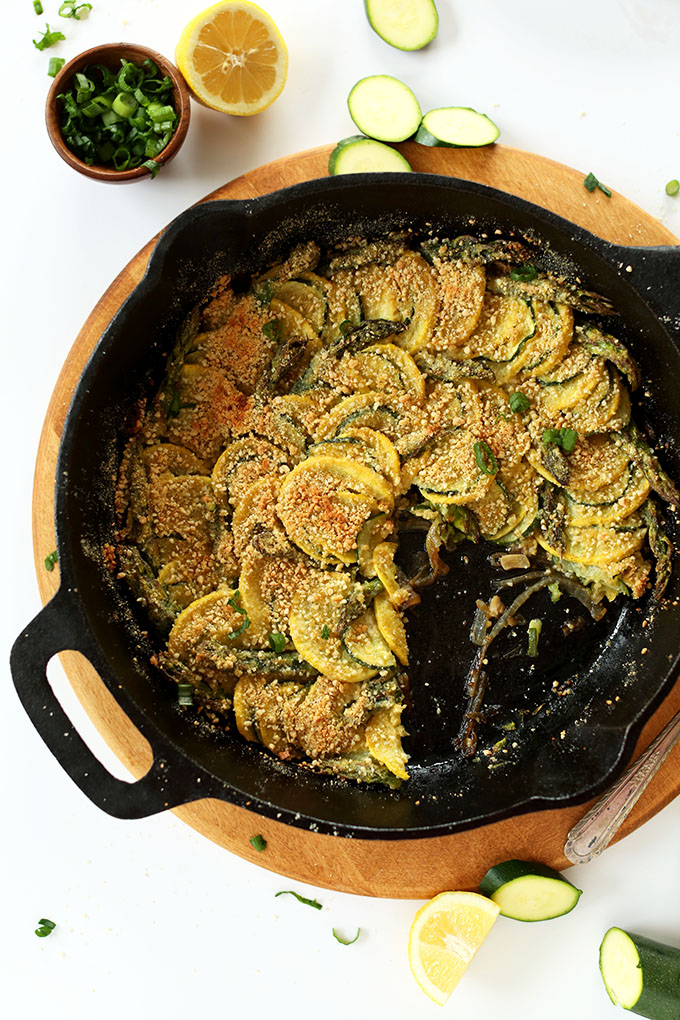 Skillet filled with delicious Vegan Parmesan Gratin alongside ingredients used to make it