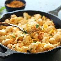 Using a fork to lift a bite of Vegan Green Chili Mac n Cheese from a skillet