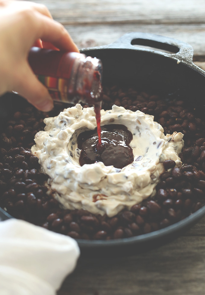 Pouring raspberry chipotle sauce into the pan to make Raspberry Chipotle Black Bean Dip