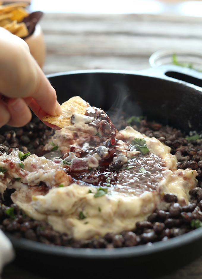 Scooping up Simple Raspberry Chipotle Bean Dip onto a chip