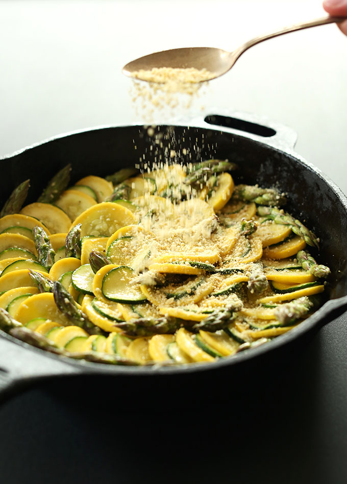 Sprinkling Vegan Parmesan Cheese onto Zucchini Asparagus Gratin