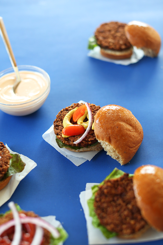 Gluten-free vegan Veggie Sliders on parchment squares with a bowl of sauce