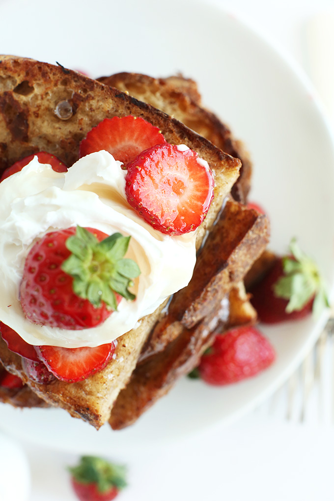 Stack of Easy Eggless French Toast topped with coconut whipped cream and fresh strawberries