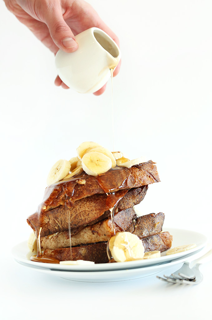Drizzling maple syrup onto a stack of Vegan Banana French Toast