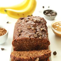 Partially sliced loaf of Chocolate PB Banana Bread topped with chocolate chips