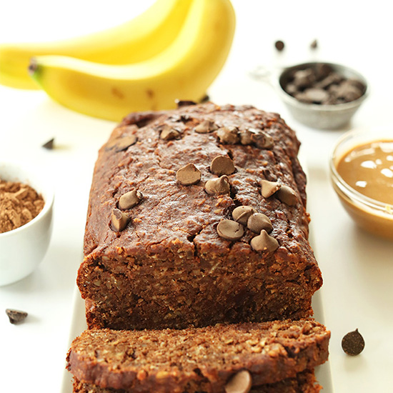 Partially sliced loaf of Chocolate PB Banana Bread topped with chocolate chips
