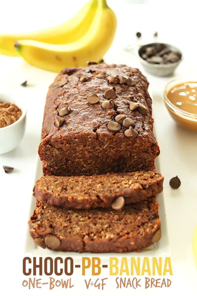 Partially sliced loaf of Chocolate Peanut Butter Banana Bread surrounded by ingredients used to make it