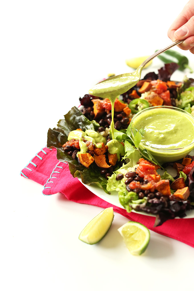 Pouring Cilantro Lime Dressing onto vegan Mexican Quinoa Salad Cups
