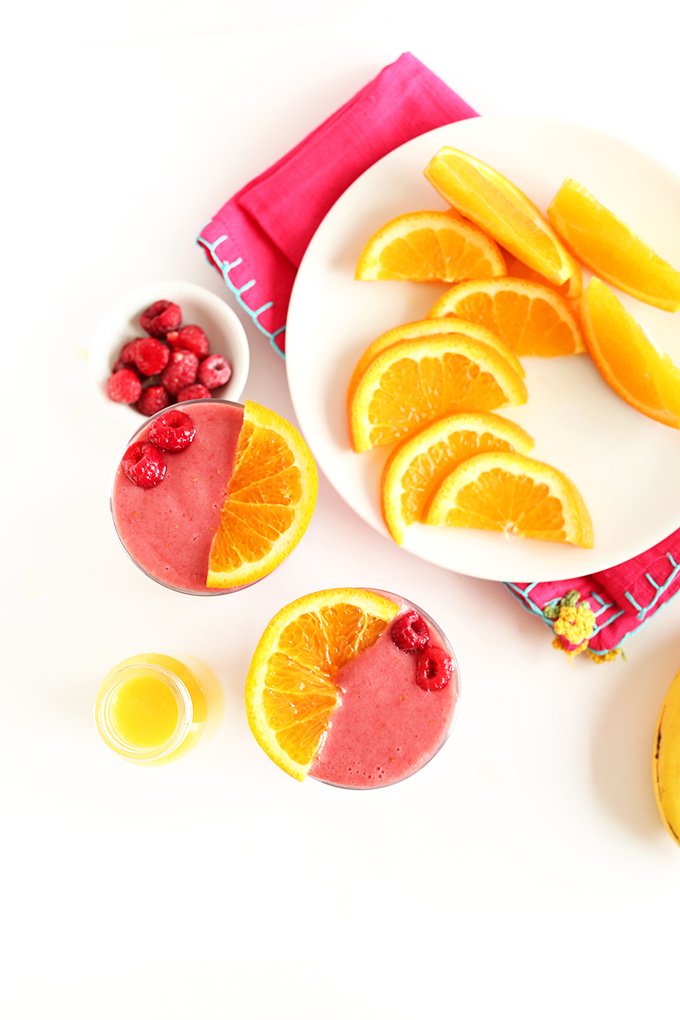 Plate of orange slices alongside two glasses of our vegan Summer in a Cup Smoothie