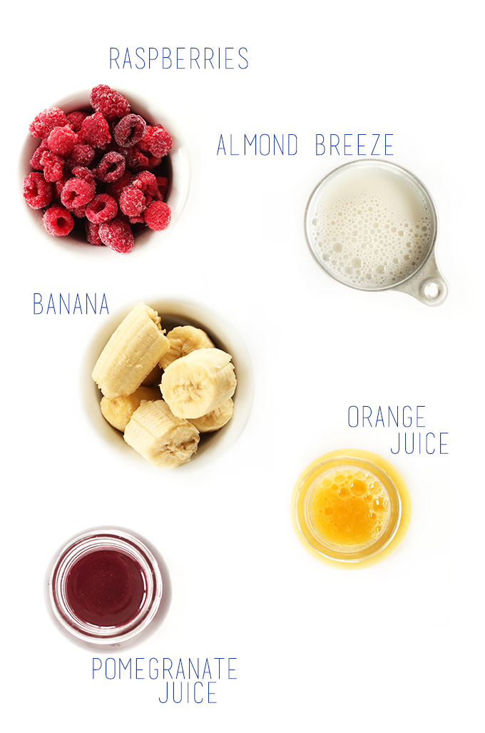 Raspberries, banana, orange juice, pomegranate juice, and almond milk for making a delicious summer smoothie
