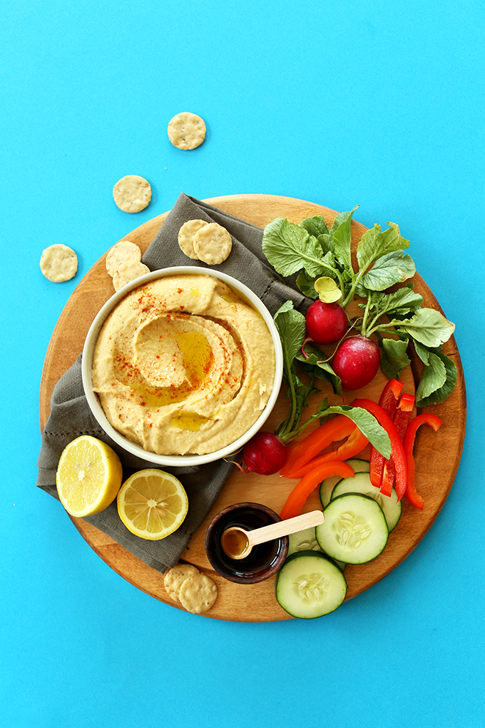 Bowl of our simple homemade Microwave Hummus on a cutting board of fresh vegetables