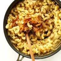 Using a wooden spoon to stir a pot of Vegan Caramelized Onion Mac 'n' Cheese