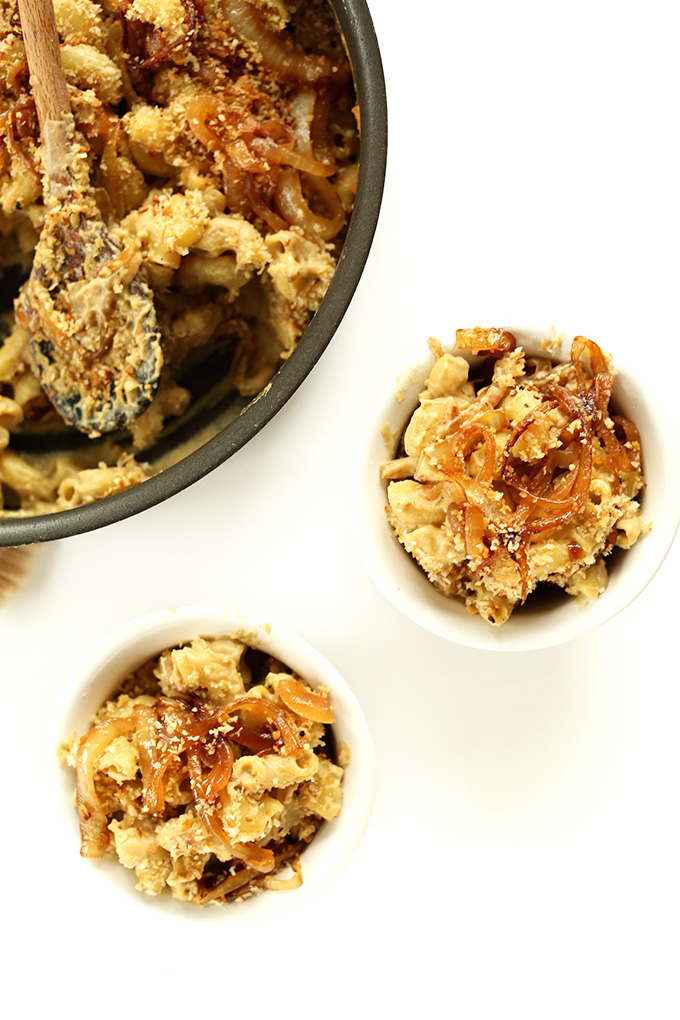 Pan and bowls filled with creamy, cheesy vegan Caramelized Onion Mac n Cheese