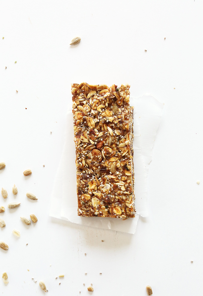 Vegan gluten-free granola bar resting on parchment paper on a white background