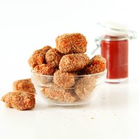 Overflowing bowl of Baked Sweet Potato Tater Tots with a jar of homemade ketchup in the background