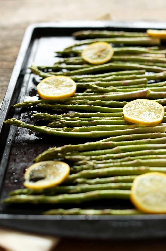 Baking sheet filled with asparagus and lemon slices ready to be roasted