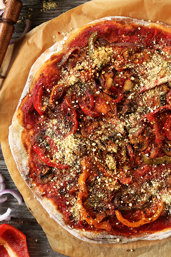 Freshly baked vegan pizza made with red sauce, sautéed veggies, and vegan parmesan