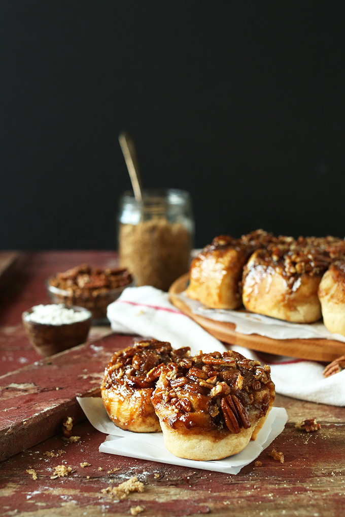 Two Vegan Sticky Buns in the foreground with the rest of the batch behind them