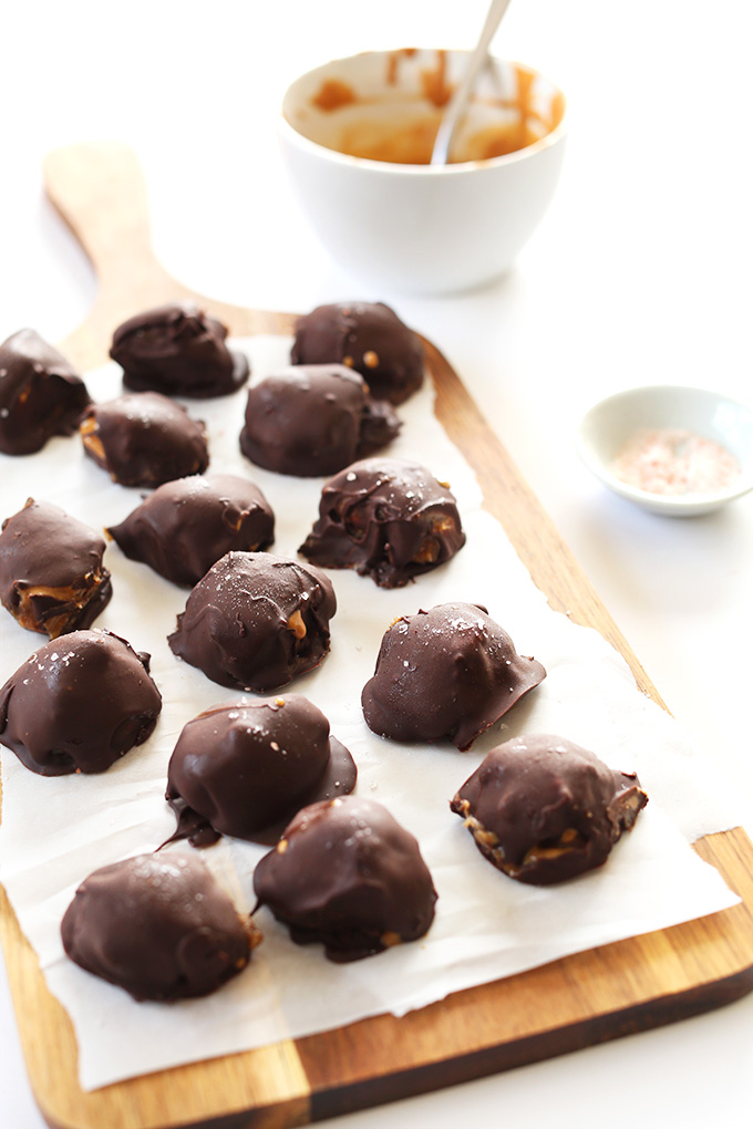 Fresh batch of our homemade Vegan Caramel Peanut Butter Truffles on a parchment-lined wood board