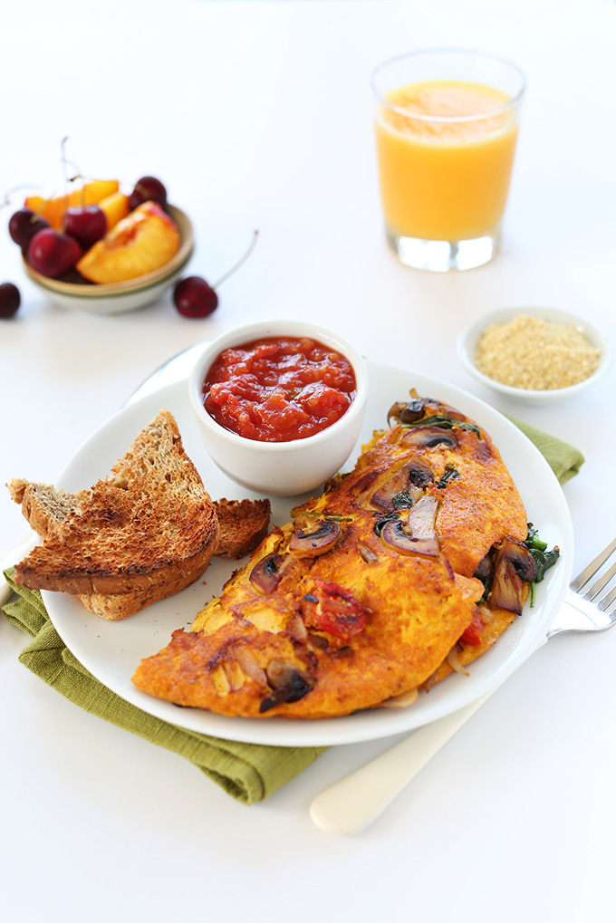 Vegan breakfast feast made with our Vegan Omelet, toast, salsa, vegan parmesan, fruit, and a glass of OJ