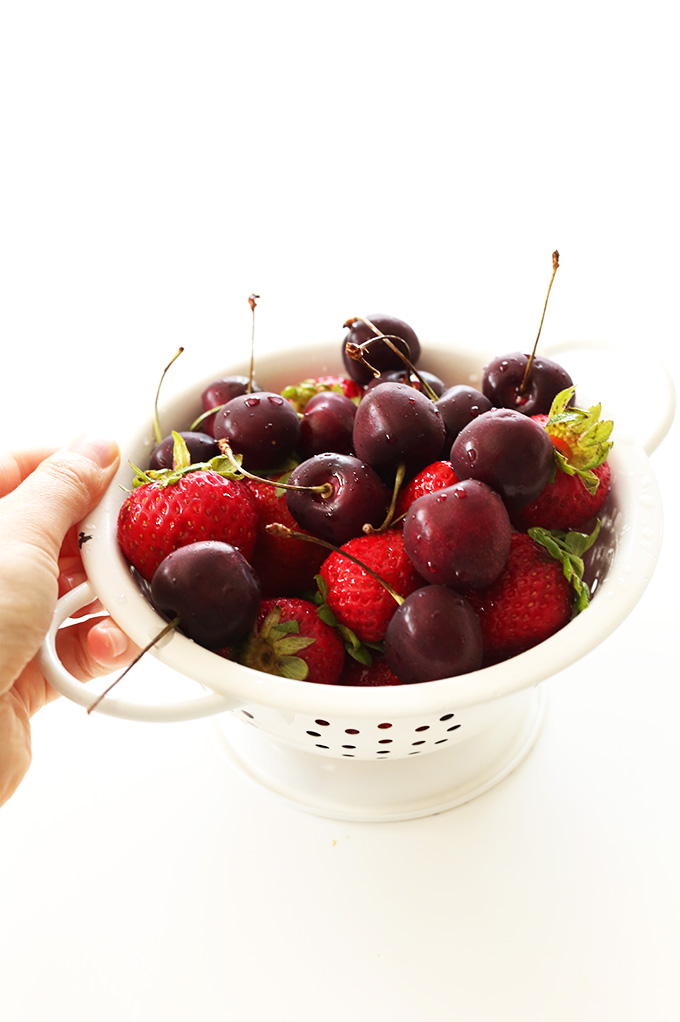 Mini colander filled with cherries and strawberries for making homemade Fresh Fruit Compote