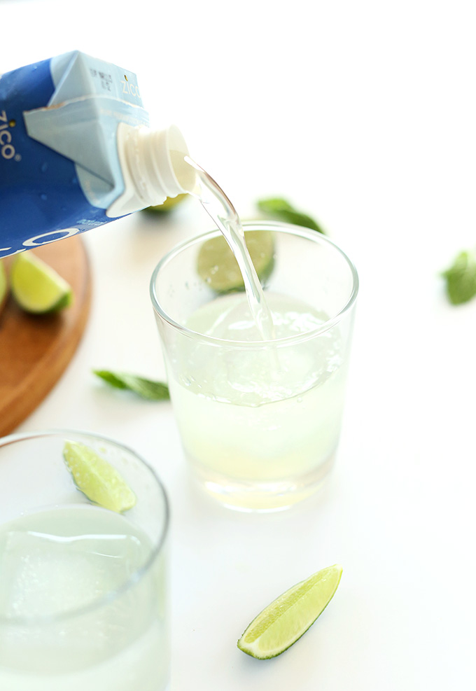 Pouring coconut water into glasses for Coconut Gin and Tonics