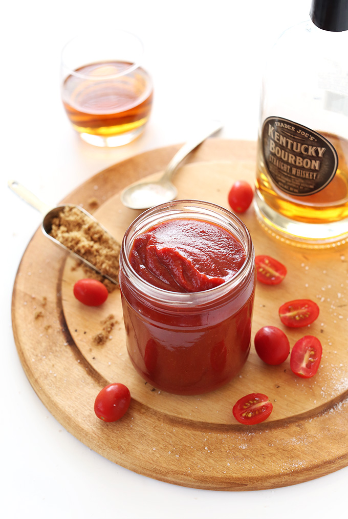 Cutting board with tomatoes, bourbon, sugar, and a jar of homemade ketchup