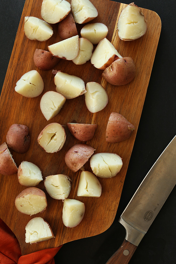 Partially cooked chopped red potatoes on a wood cutting board