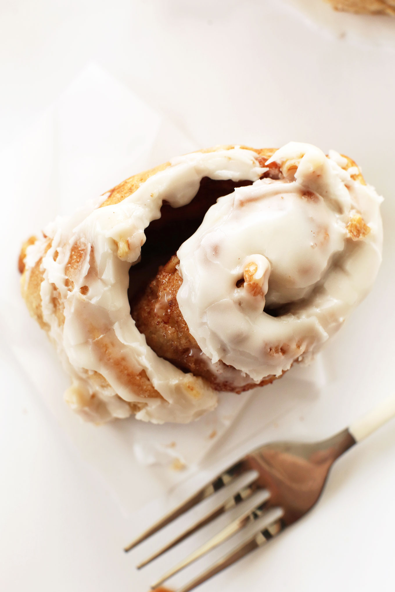 Partially unrolled gooey Banana Bread Cinnamon Roll with icing