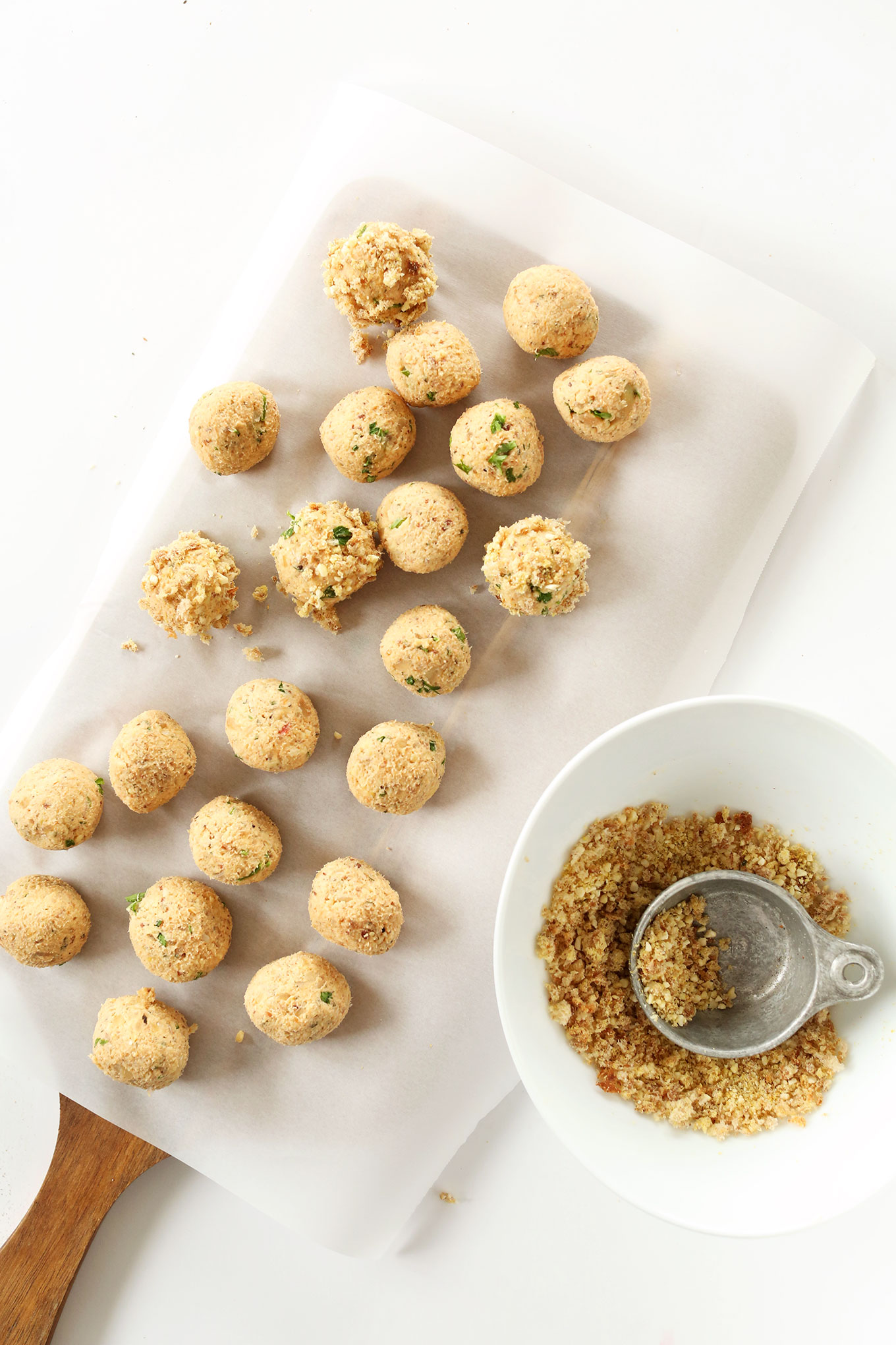 Freshly rolled vegan tempeh meatballs resting on a parchment-lined cutting board
