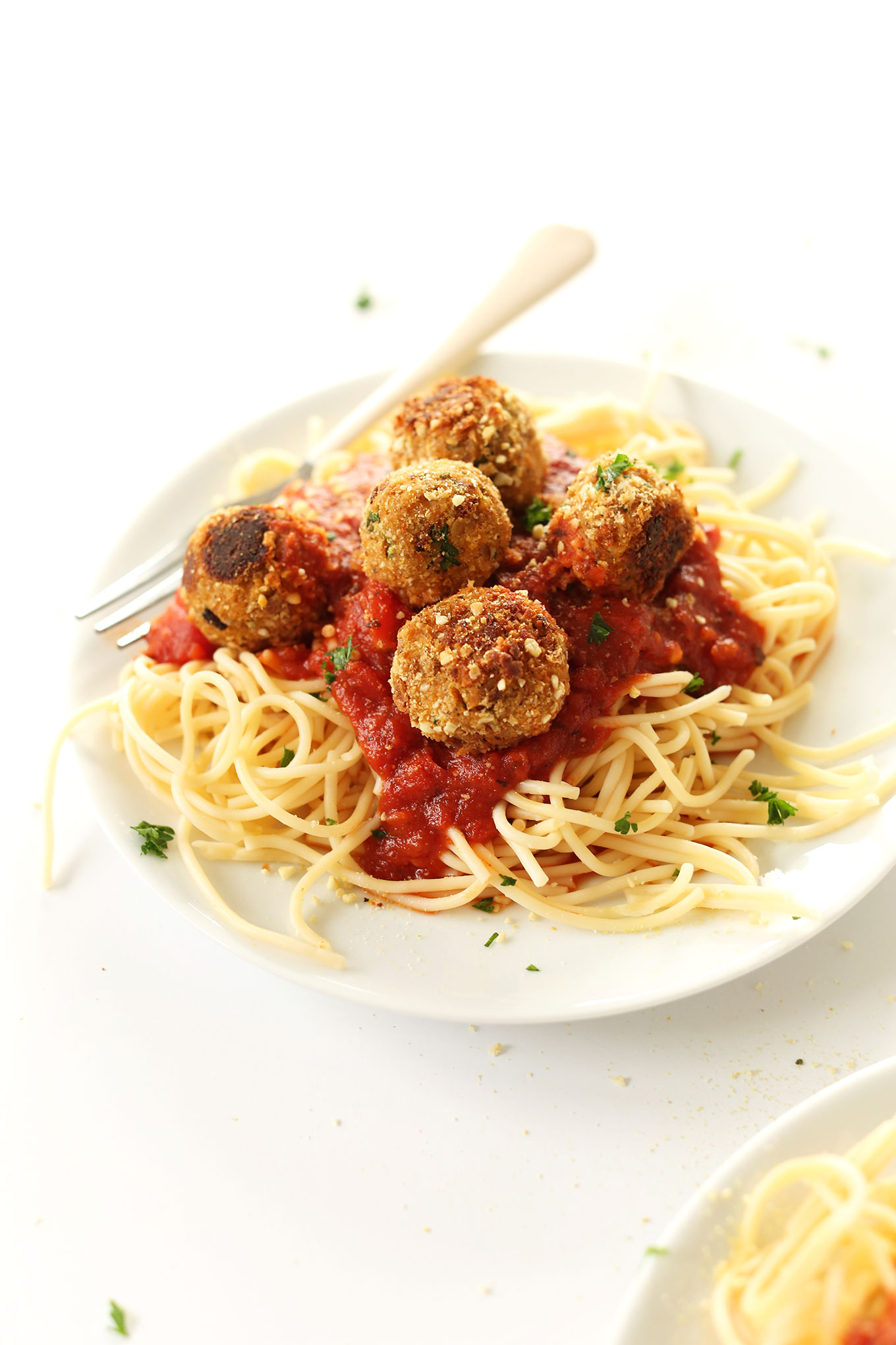 Close up shot of a plate loaded high with pasta, marinara, and homemade vegan meatballs