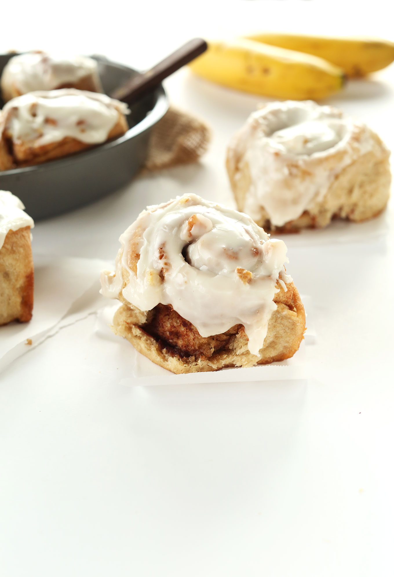 Freshly baked Vegan Banana Bread Cinnamon Rolls displayed on squares of parchment paper