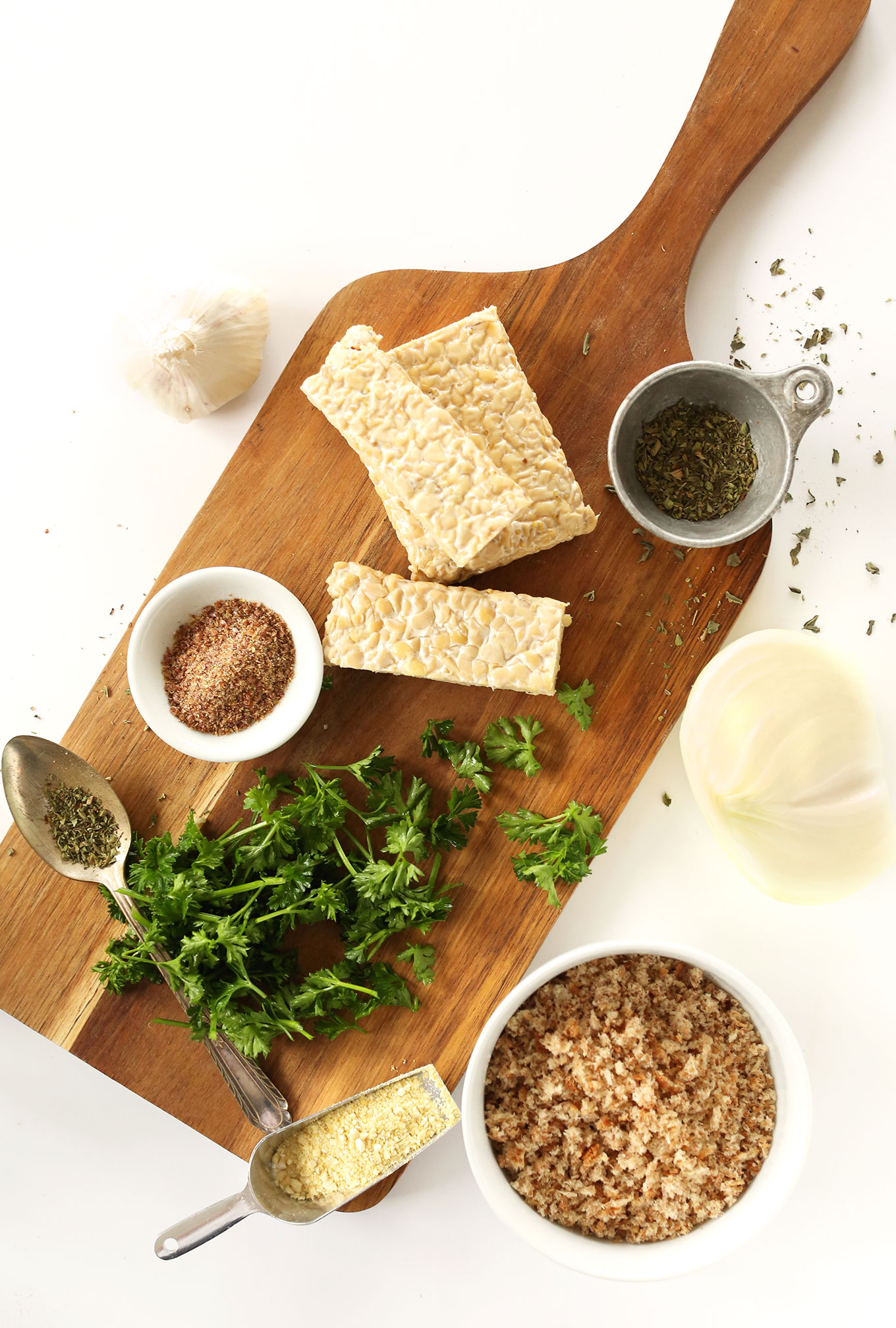 Cutting board featuring tempeh and seasonings to make delicious vegan tempeh meatballs
