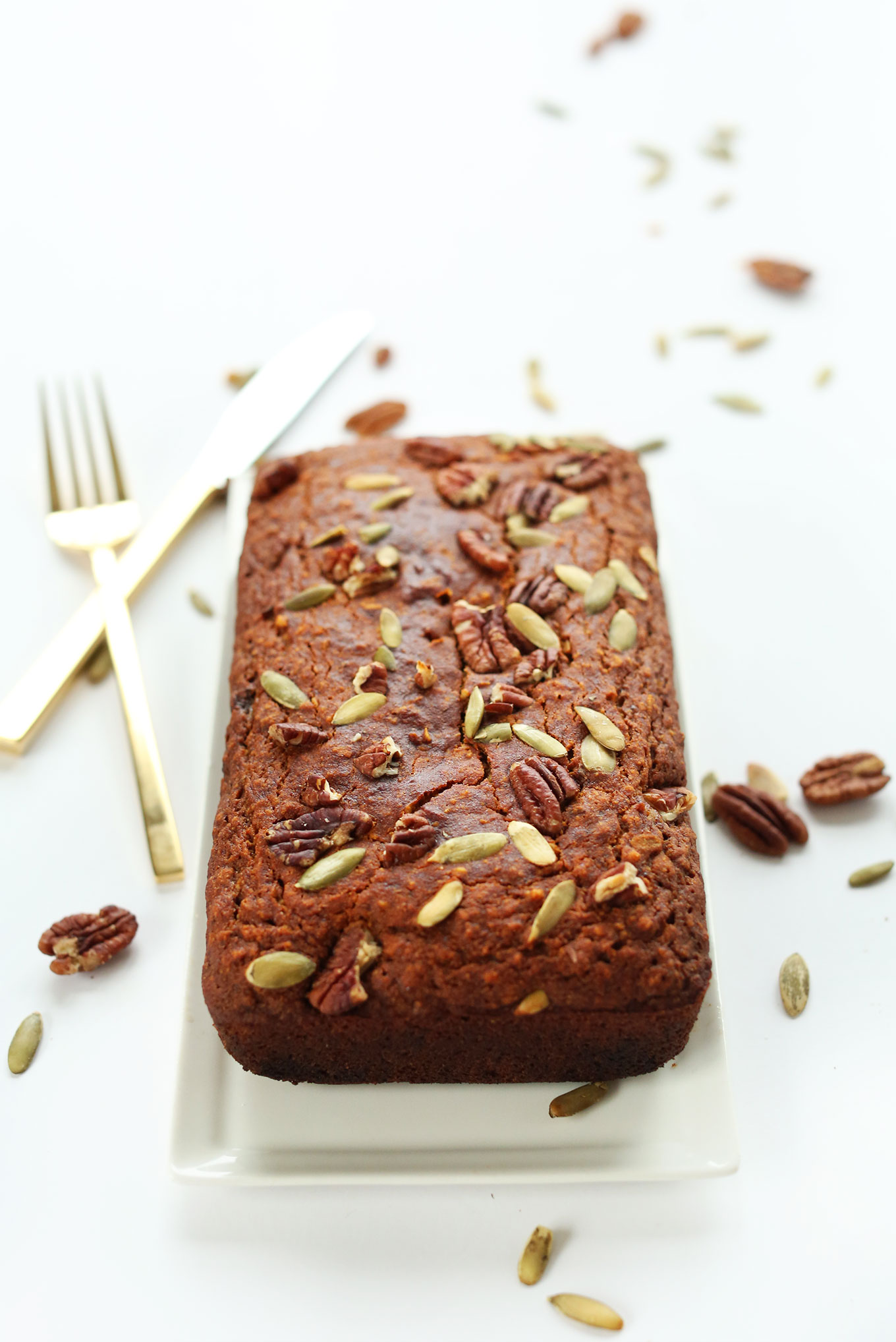 Loaf of Vegan GF Pumpkin Bread topped with pecans and pepitas