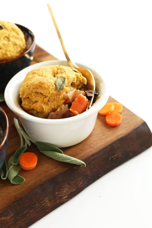Wood cutting board featuring bowls of our Vegan Fall Pot Pies loaded with veggies