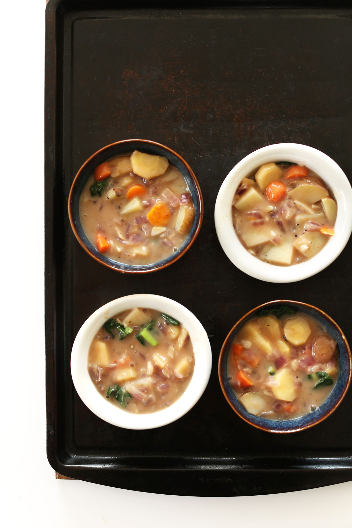 Baking sheet with bowls showing the vegetable layer of our Fall Pot Pies