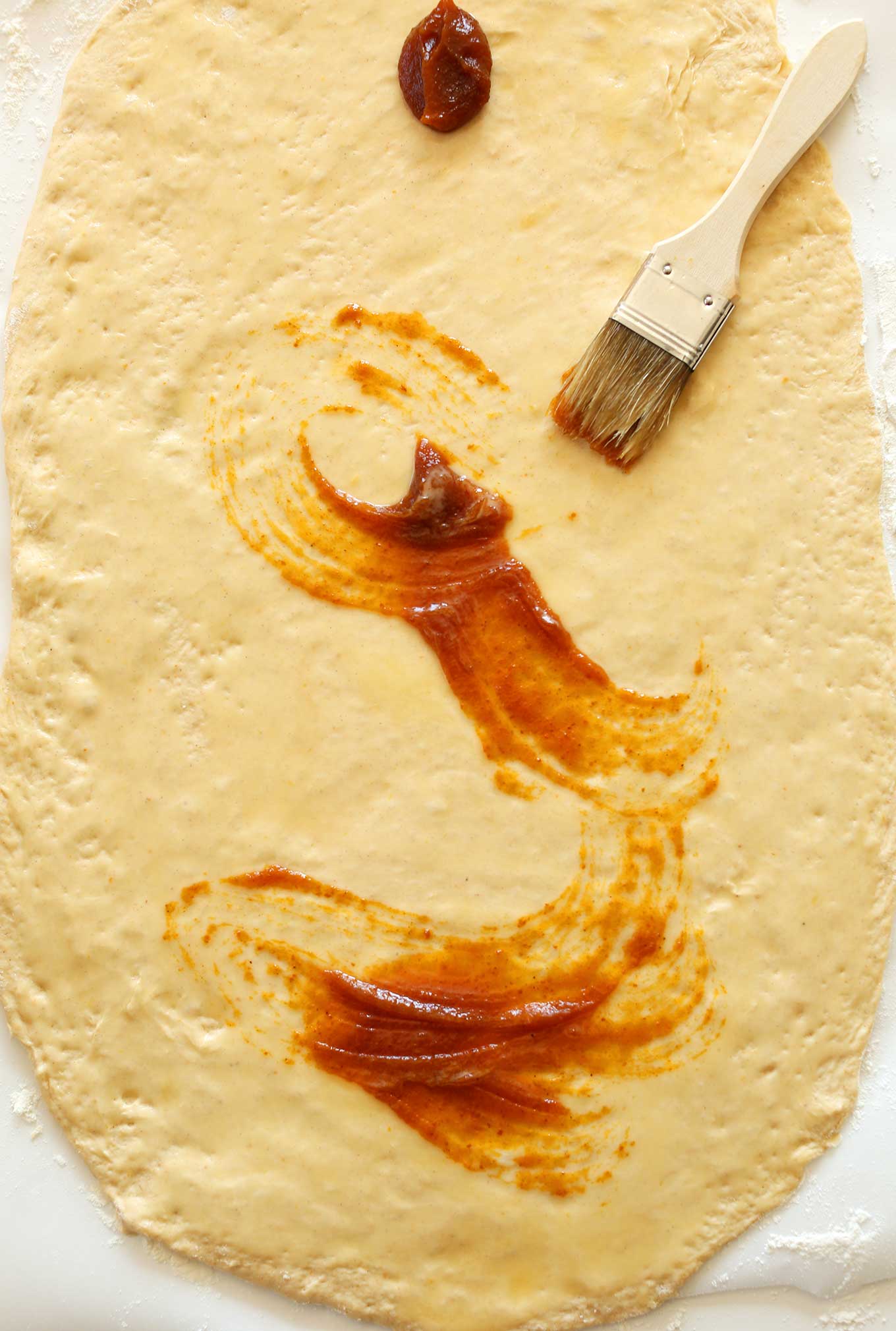 Spreading pumpkin filling onto rolled out cinnamon roll dough