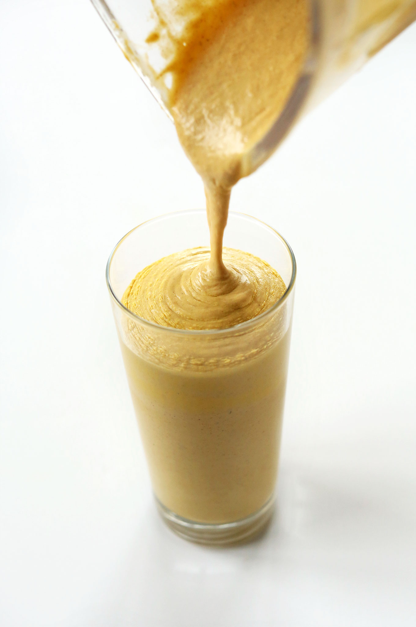 Pouring Bourbon Pumpkin Milkshake into a tall glass