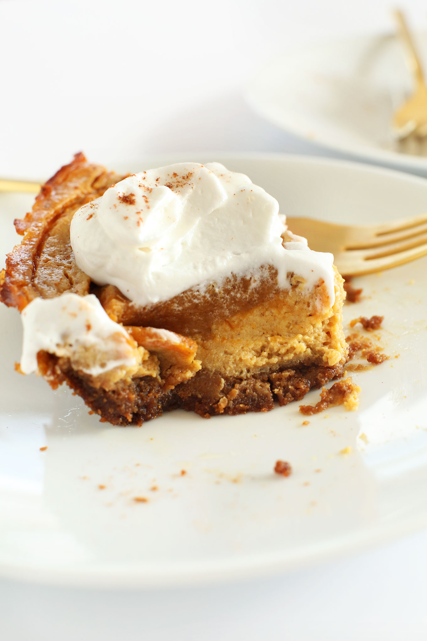 Side view of a partially eaten slice of pumpkin swirl cheesecake with coconut whip