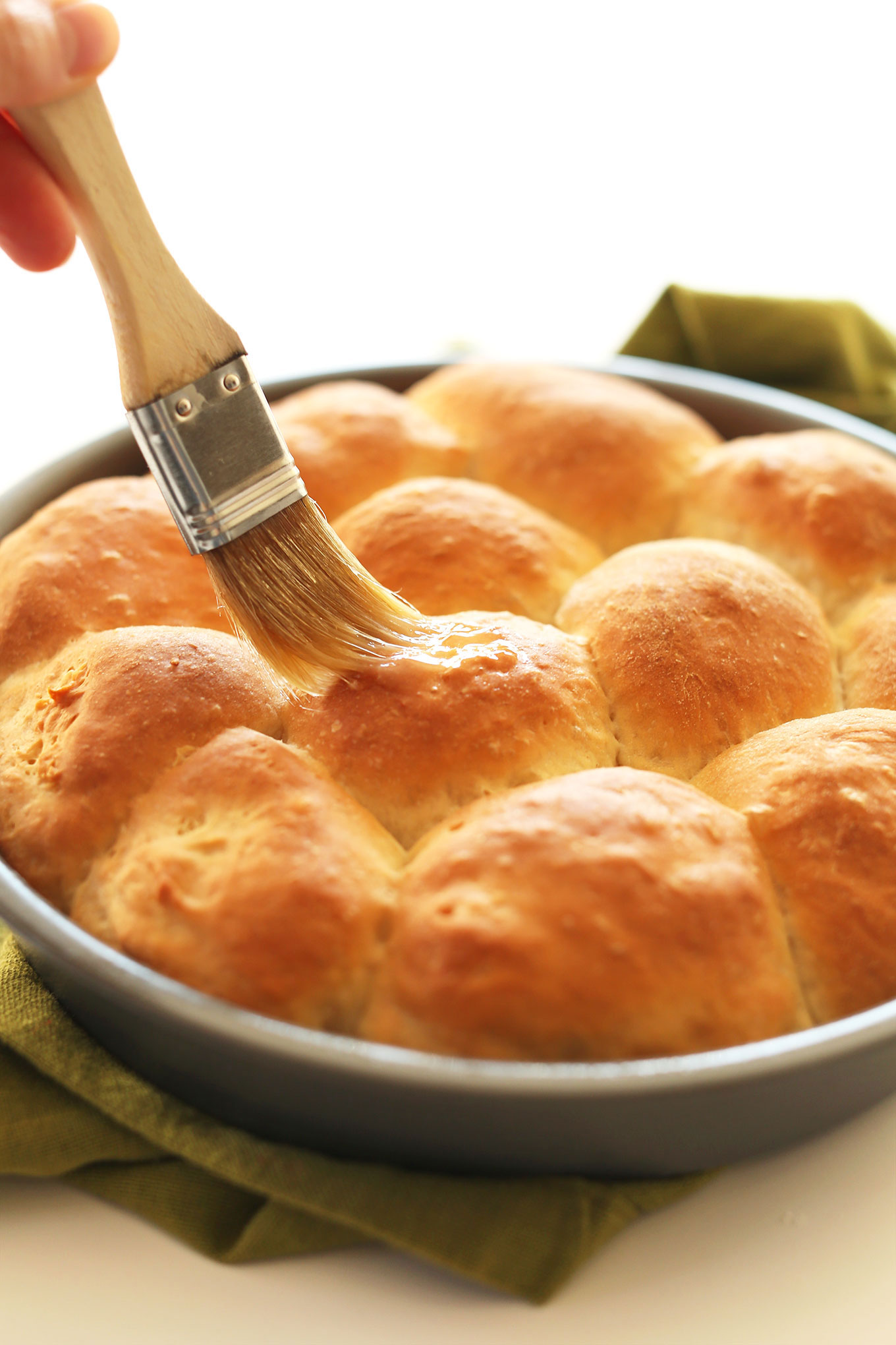 Brushing vegan butter onto homemade vegan dinner rolls
