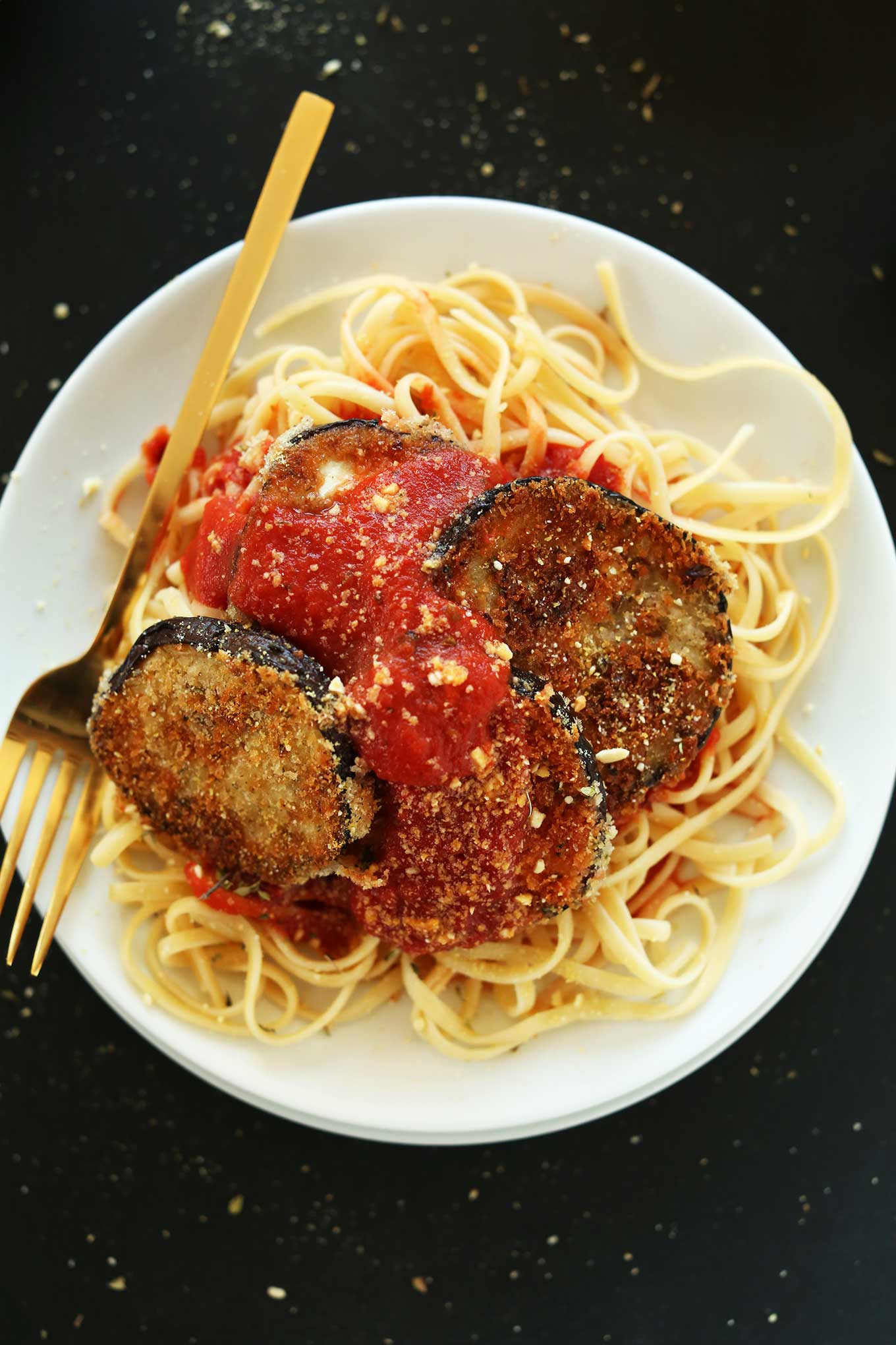 Big bowl of linguine noodle topped with marinara and vegan eggplant parmesan