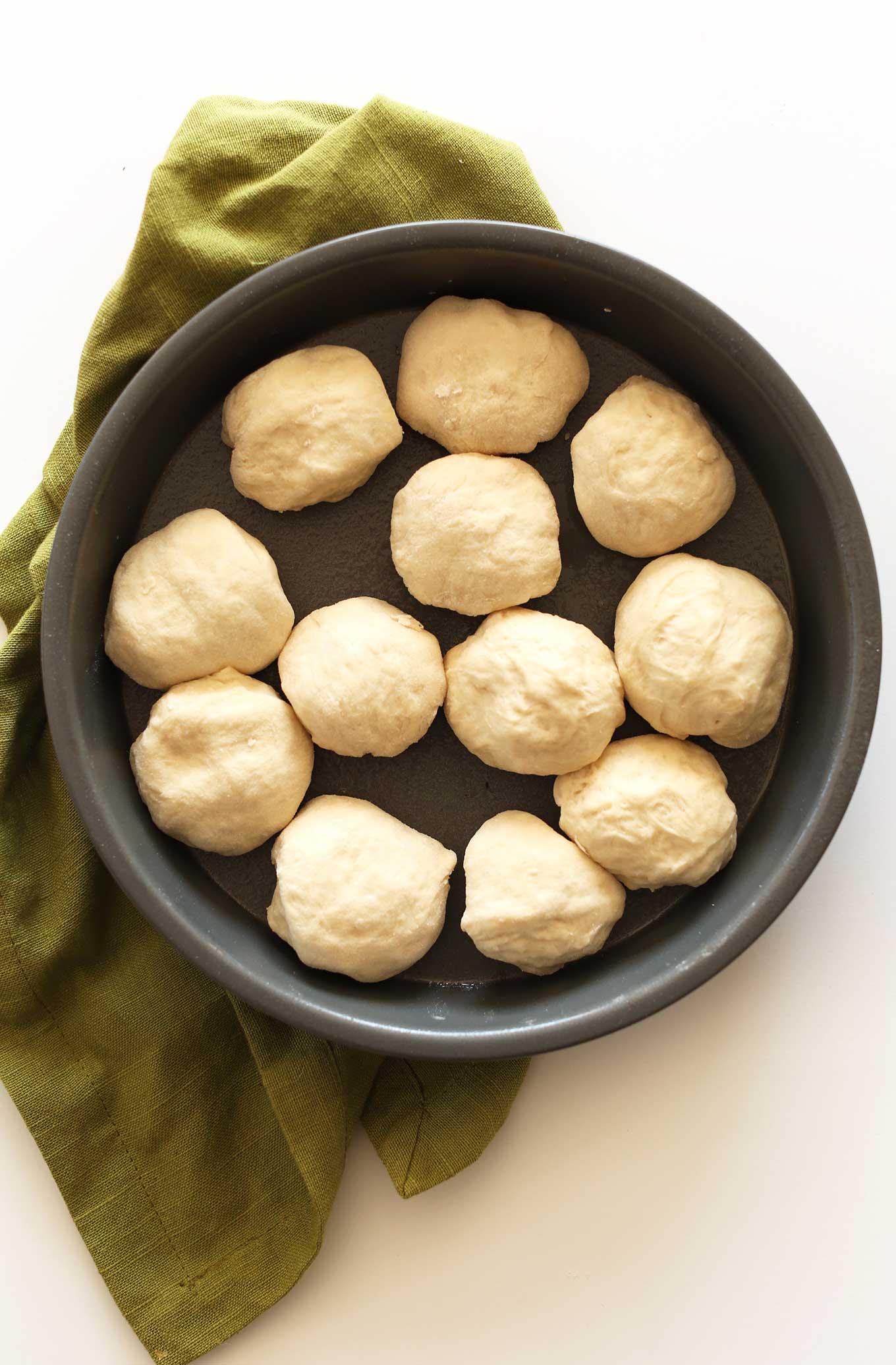 Freshly made vegan dinner rolls proofing in a pan