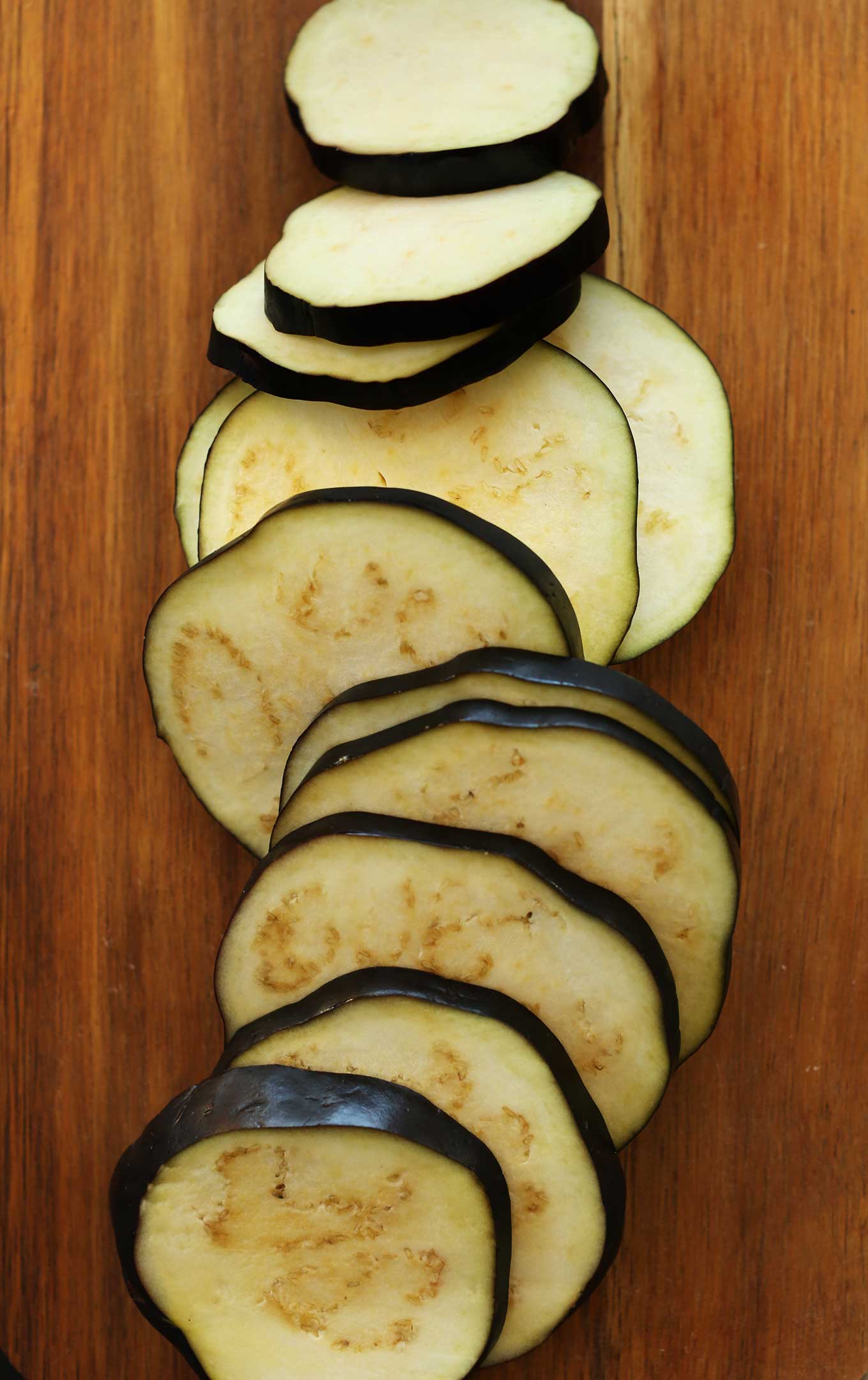 Thinly sliced eggplant on a cutting board